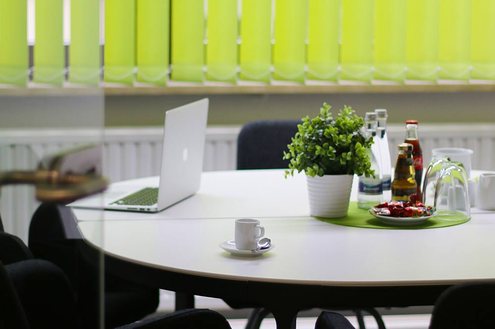 Tisch, auf dem ein Buchsbaum, ein Laptop und eine Tasse gehen