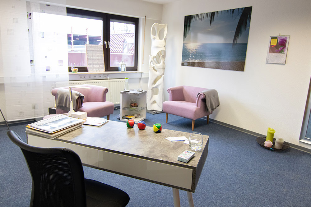 Büro, im Hintergrund rosane Sessel und Skulptur im Hintergrund